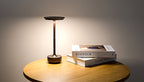 Rechargeable table lamp with warm glowing top and gold base on side table