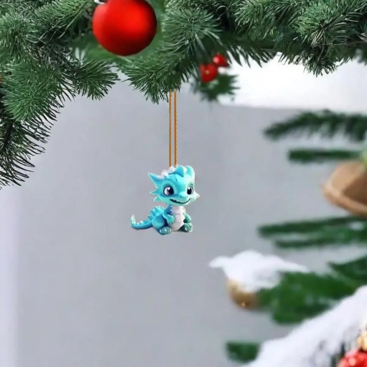 Small blue cartoon dragon keychain pendant hanging from pine branch