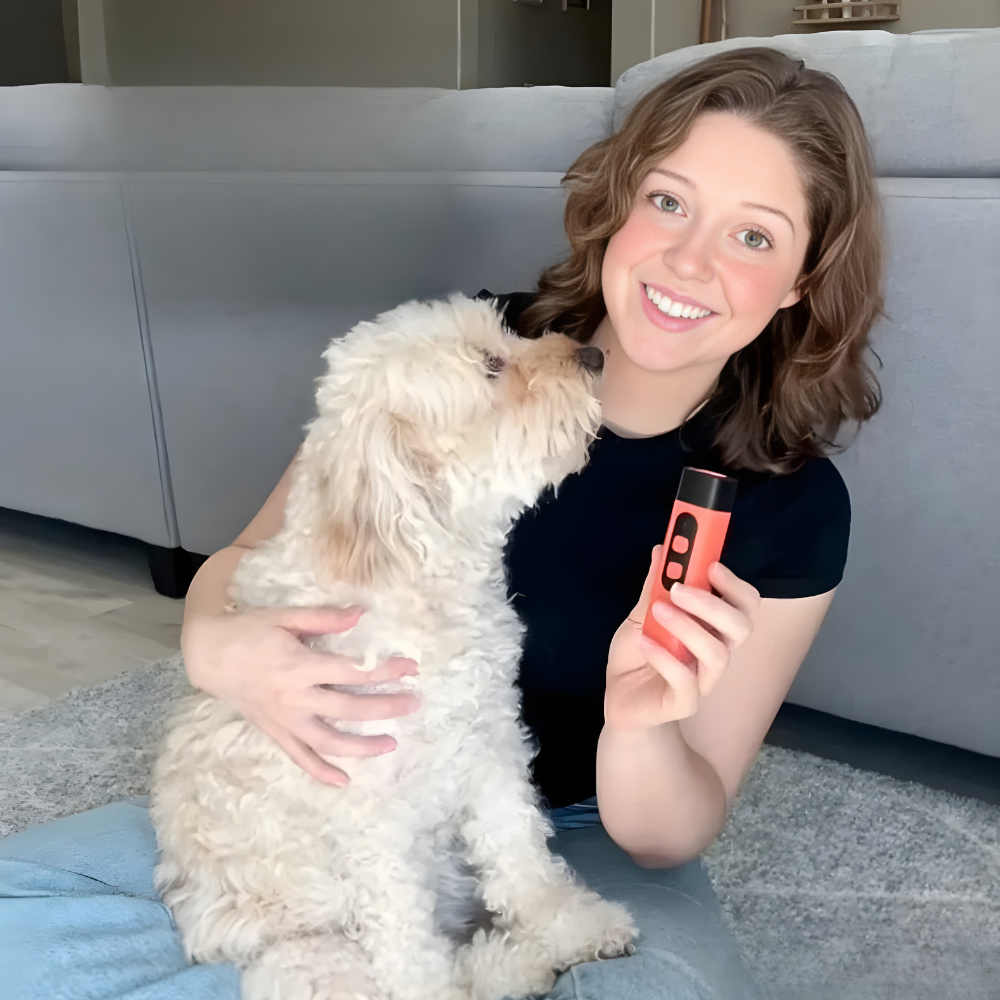 Orange and black handheld ultrasonic dog trainer device held next to a dog