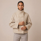 Beige pea coat with high funnel neck, double-breasted buttons and welt pockets