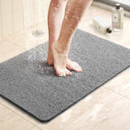 Gray textured shower mat with anti-slip surface, foot stepping on it in shower