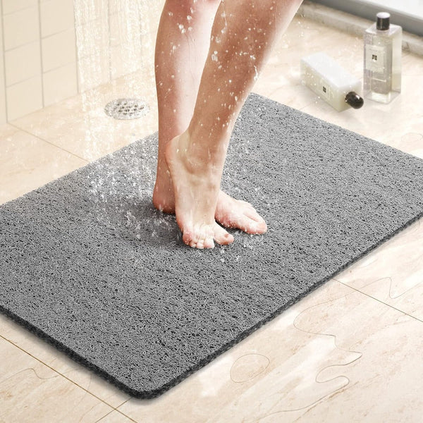 Gray textured shower mat with anti-slip surface, foot stepping on it in shower