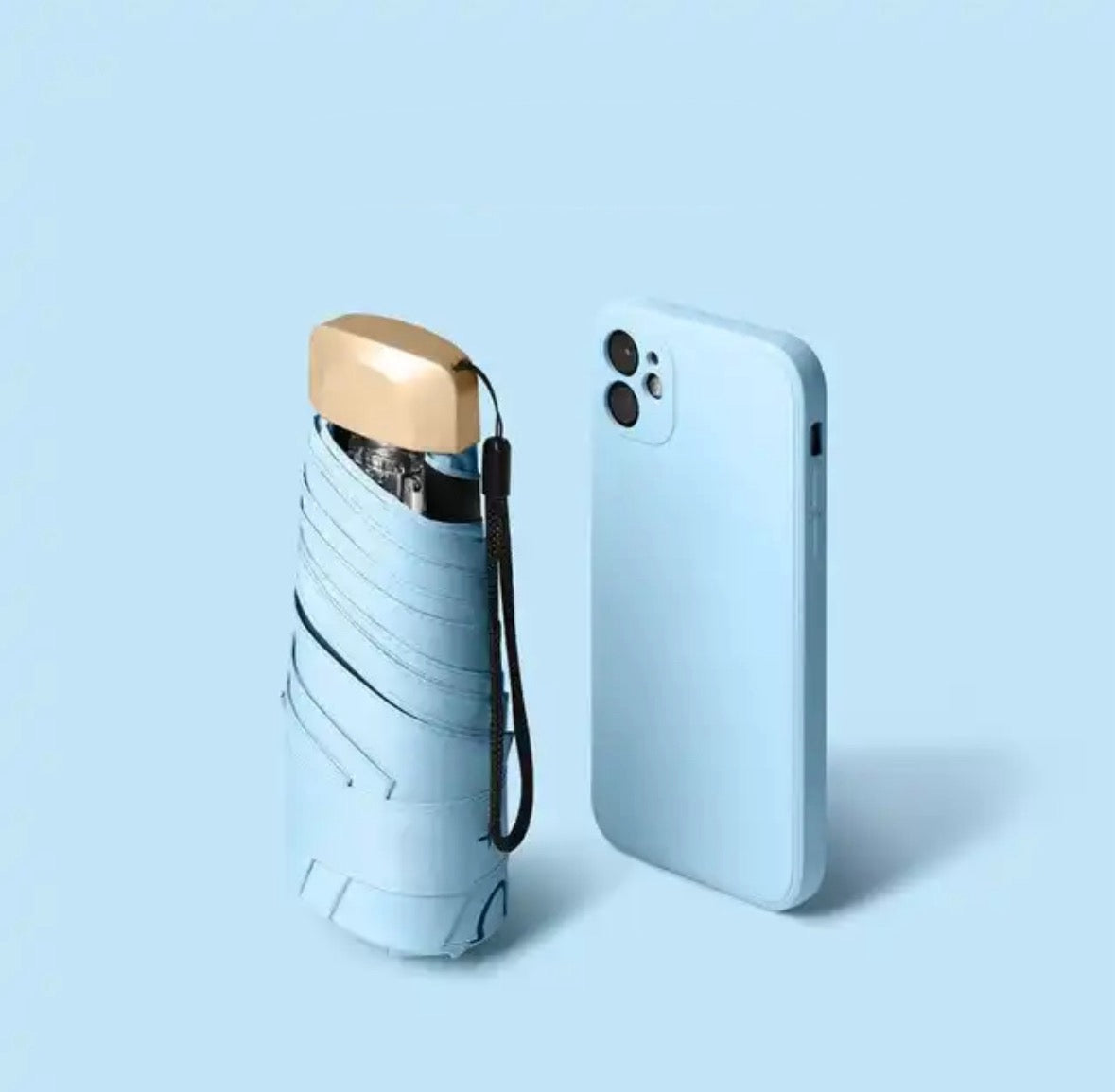 Light blue mini travel umbrella, folded pocket size with carry strap and gold cap.