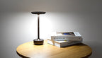 Rechargeable table lamp with warm glowing top and dark base on wooden surface