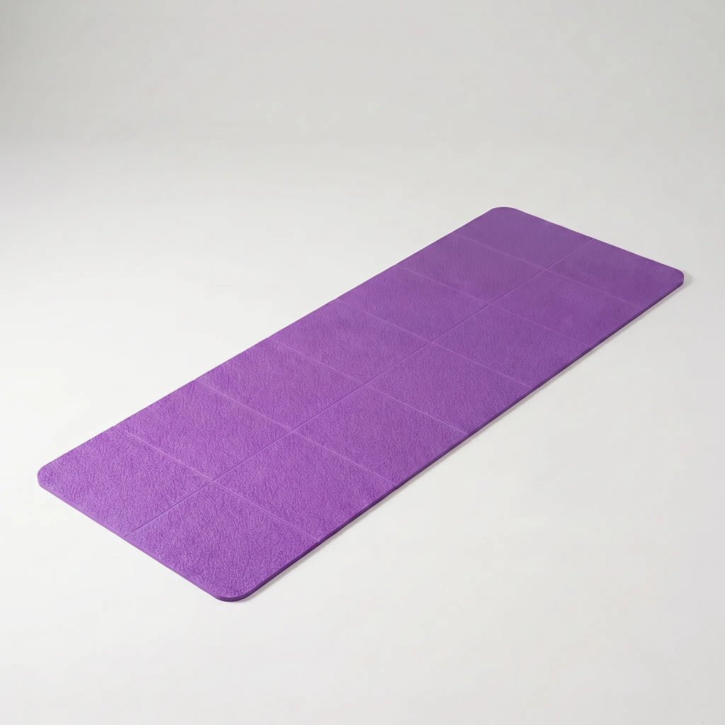 Purple foldable yoga mat laid flat, diagonal view showing textured grip surface