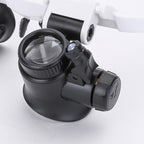 LED magnifier headband close-up: black lens housing with clear glass lens