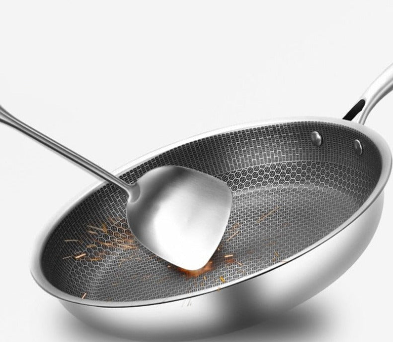 Non-stick frying pan with honeycomb textured surface and stainless serving spoon