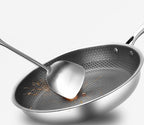 Non-stick frying pan with honeycomb textured surface and stainless serving spoon