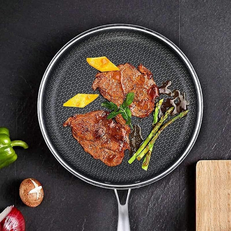 Non-stick stainless skillet with honeycomb interior holding seared meat and herbs