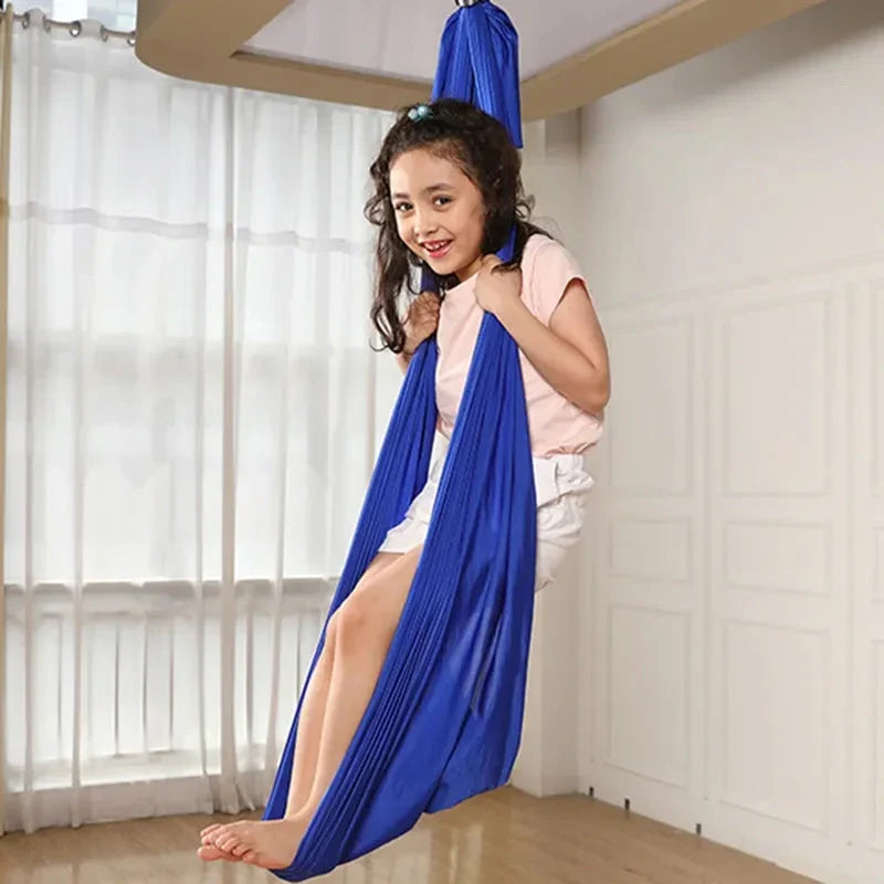 Blue kids' cotton hammock swing cocoon, child standing inside with arms up.