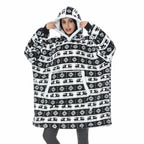 Black-and-white patterned oversized wearable blanket hoodie with hood and sherpa-style lining.
