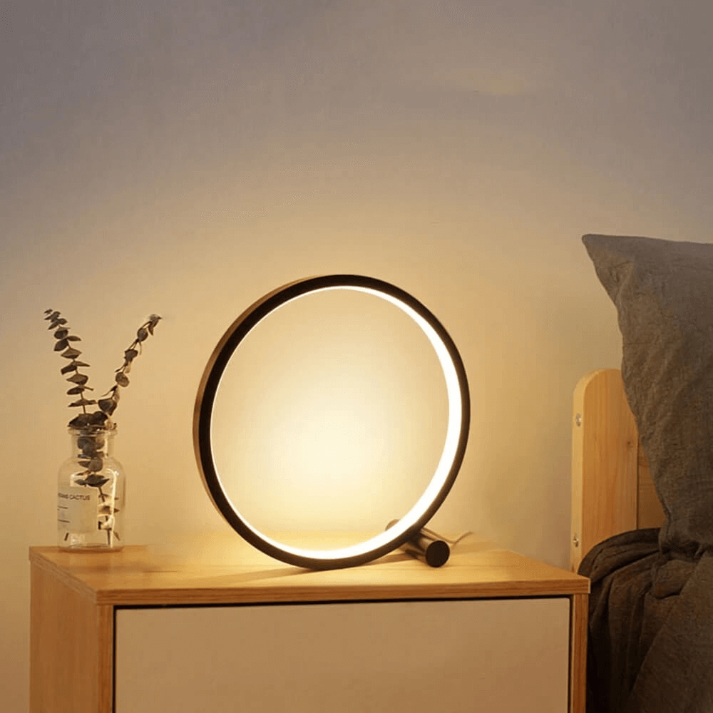 Minimalist round LED table lamp on side table, glowing halo ring, dark control knob