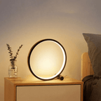 Minimalist round LED table lamp on side table, glowing halo ring, dark control knob