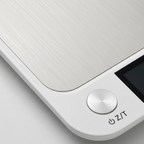 White digital scale close-up with round buttons and edge LCD display