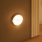 Round warm-white LED motion sensor light on hallway wall, glowing