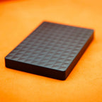 Black external hard drive with geometric textured top, compact rectangular design