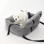 Gray dog booster bed with black straps, plush interior, and small white dog