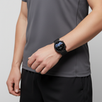 Round black smartwatch on wrist with dark dial and black strap