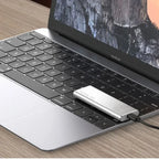 Silver portable external SSD plugged into a laptop with USB cable.