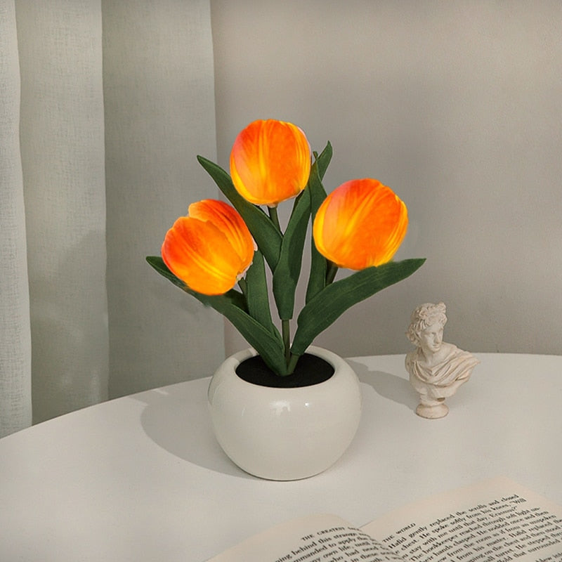 Orange tulip night light blooms in a white ceramic pot with warm LED glow