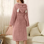 Dusty pink plush bathrobe with bunny-ears hood and white paw details, tied belt, long sleeves.