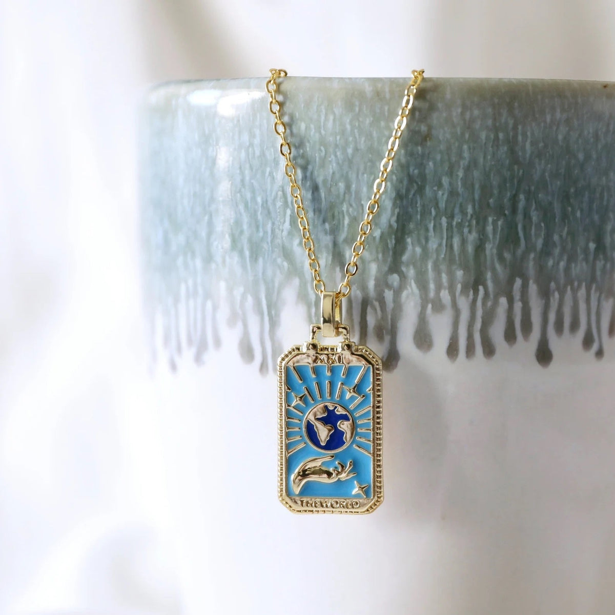 Gold-tone tarot card necklace with blue enamel design and winged dove in center, link chain