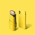 Compact travel umbrella, folded yellow with wrist strap and protective cover