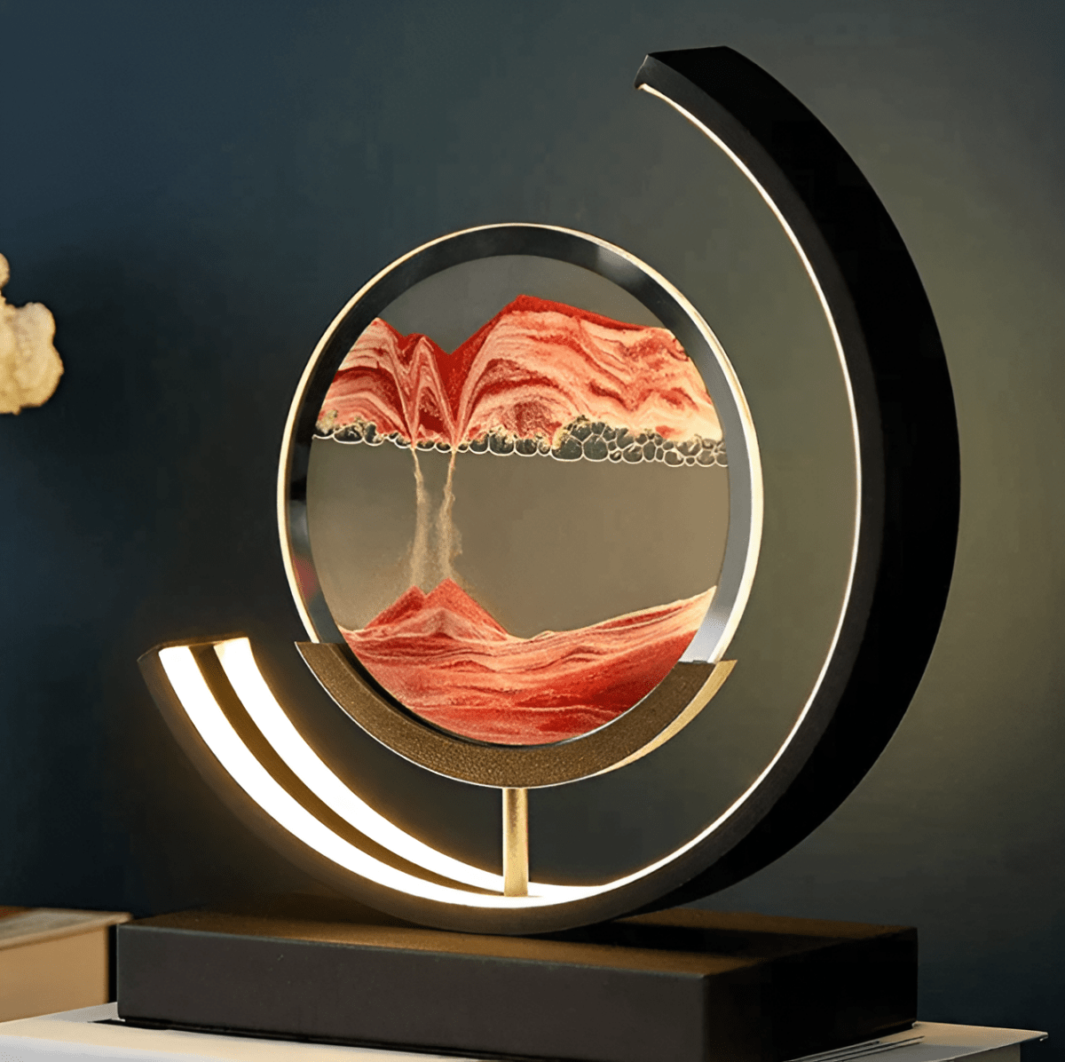 Moving sand LED lamp with circular red sand art, glowing silver ring and black base