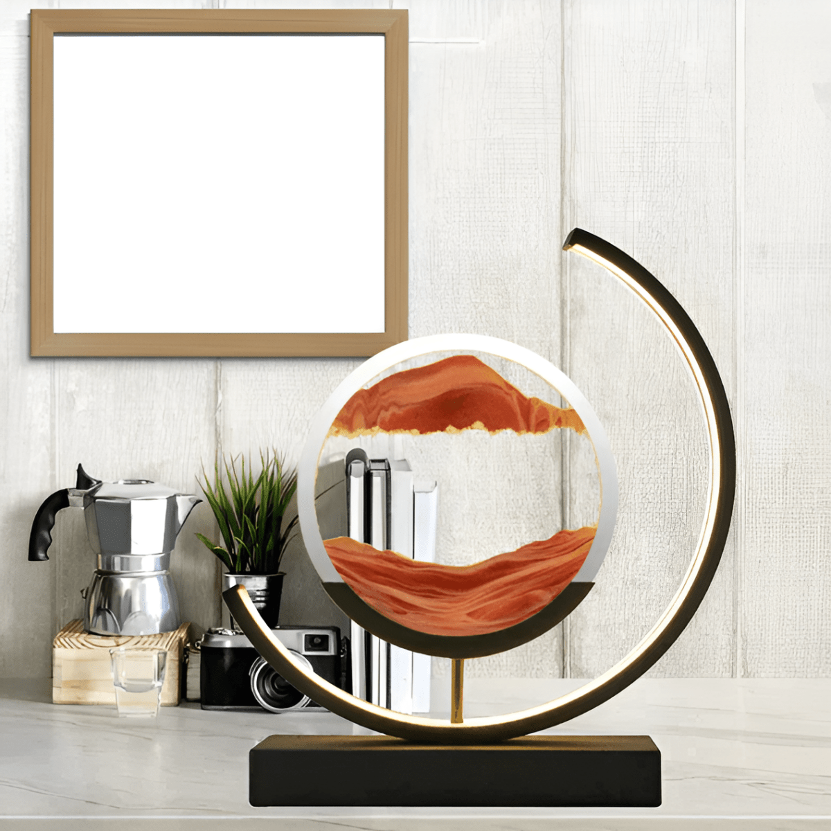 Moving sand LED lamp with circular red sandscape and glowing crescent ring on black stand
