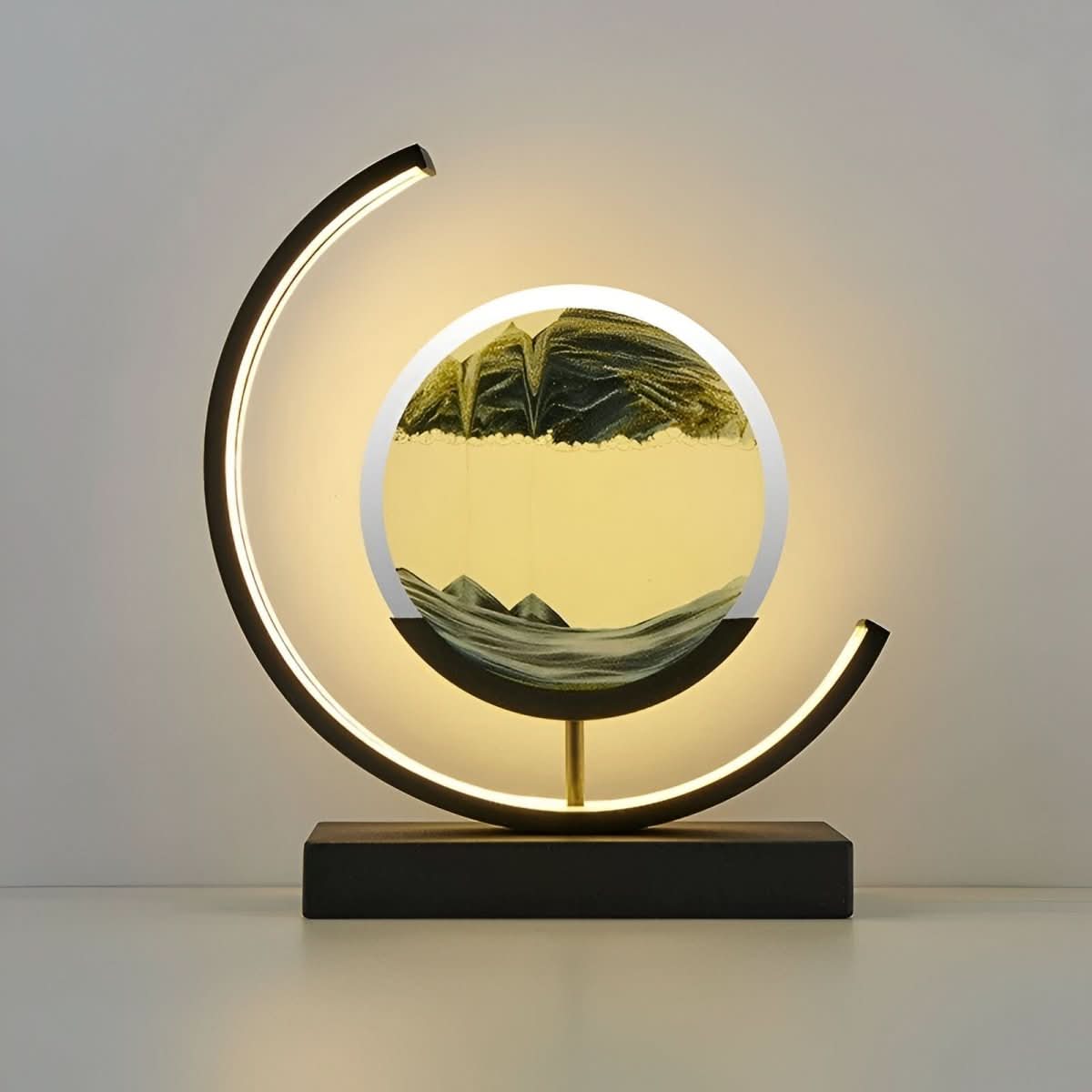 Moving sand LED lamp with circular green sand art and glowing crescent ring on dark base