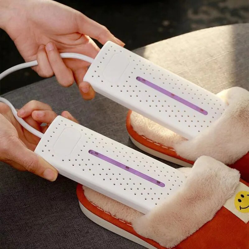 White shoe dryers plugged in on a couch, fitted into boots with purple bars on.