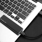 Black portable external SSD connected to a laptop via USB cable.