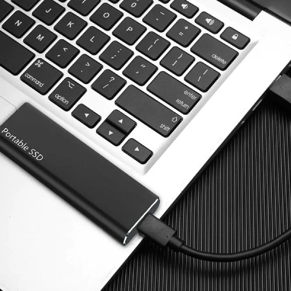 Black portable external SSD connected to a laptop via USB cable.