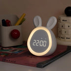 Pink bunny-shaped kids alarm clock with LED night light glowing and digital time display