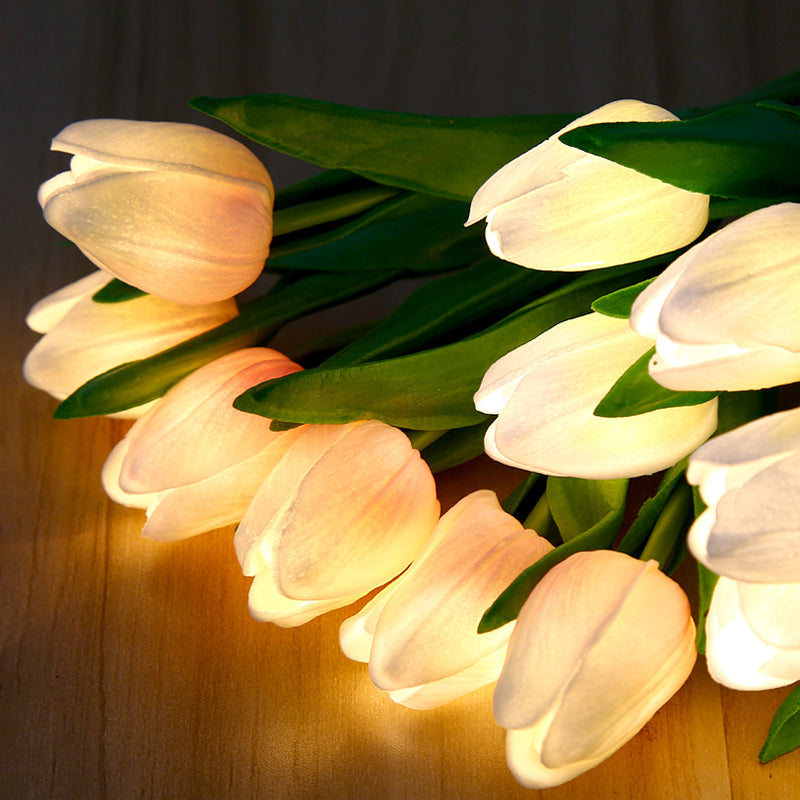White tulip night light blooms with green leaves, warm LED lighting detail
