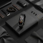 Black activity tracker smartwatch with colored display, centered on a dark tray