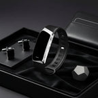 Black fitness tracker with silver side frame and band, shown on a matte tray
