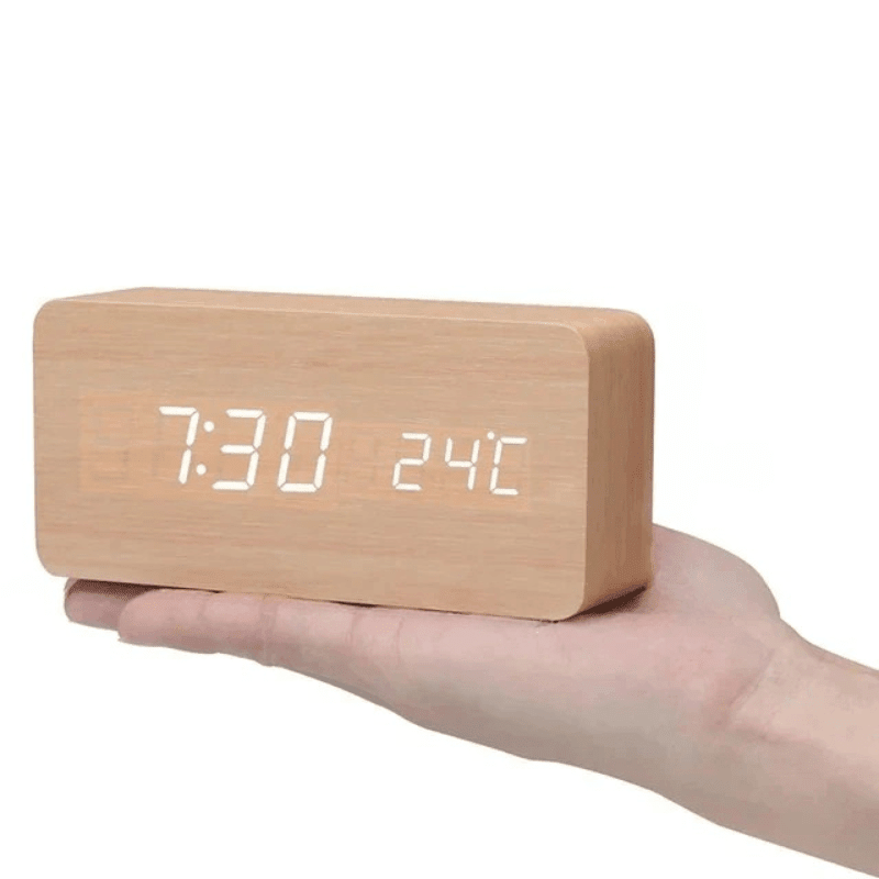 Light tan wooden LED digital clock with white digits, shown in hand