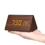 Dark wood LED digital clock with amber time digits on angled stand, held in hand