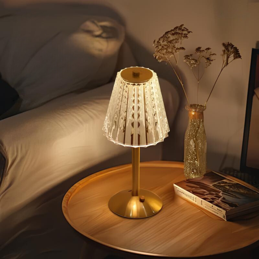 Crystal table lamp with gold base and ribbed crystal shade, warm light glow