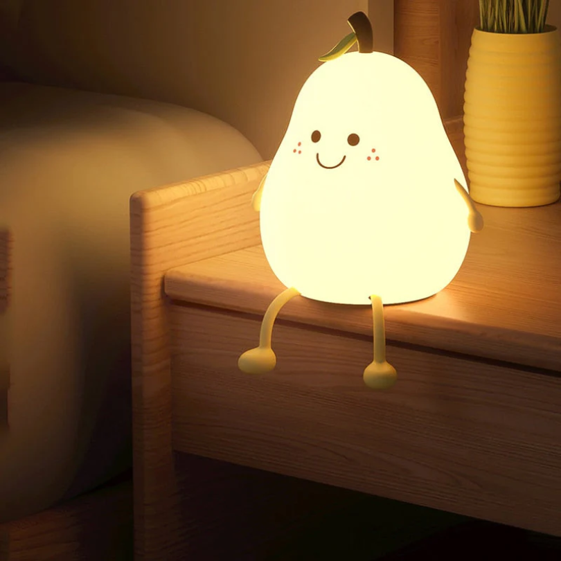 Glowing pear-shaped kids night light with smile and green leaf on wooden shelf