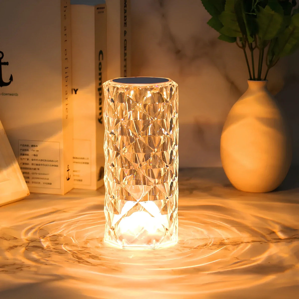 Faceted crystal table lamp glowing amber/gold with cylindrical crystal shade.