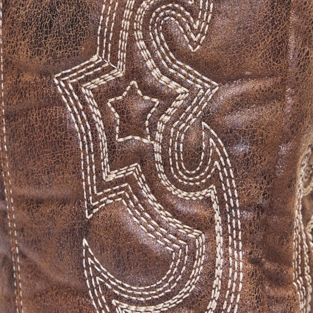Women's brown boots close-up of ornate white decorative stitching on suede