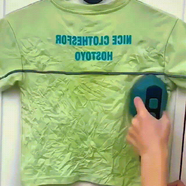 Green mini steam iron steaming a green shirt on a surface