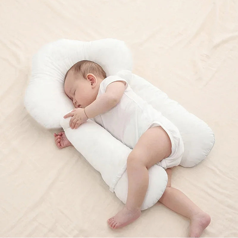 White ergonomic baby cushion laid flat with a baby positioned on top