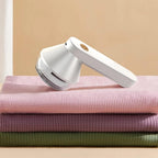 Rechargeable fabric shaver, white handheld electric lint remover on stacked knit fabric