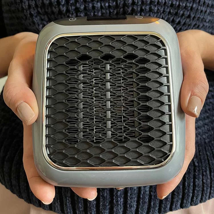 Portable electric heater held in hands, showing front grille and glowing coils