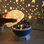 Starry sky night light with black star dome and blue base, glowing with hand nearby