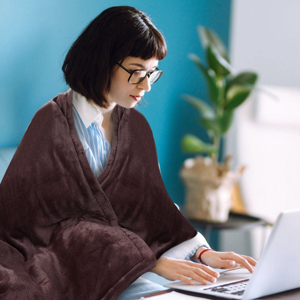 Burgundy flannel electric blanket draped over shoulders while typing on laptop