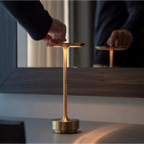 Touch-controlled rechargeable table lamp with warm glow on gold stem and base